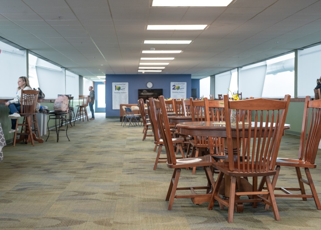 Member lounge with tables and chairs beside large windows